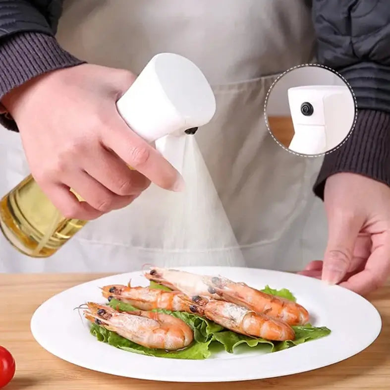 A person using a spritz oil spray on shrimp and lettuce on a white plate, demonstrating cooking with precision.